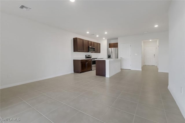 kitchen featuring dark brown cabinets, a center island, light tile patterned flooring, and appliances with stainless steel finishes