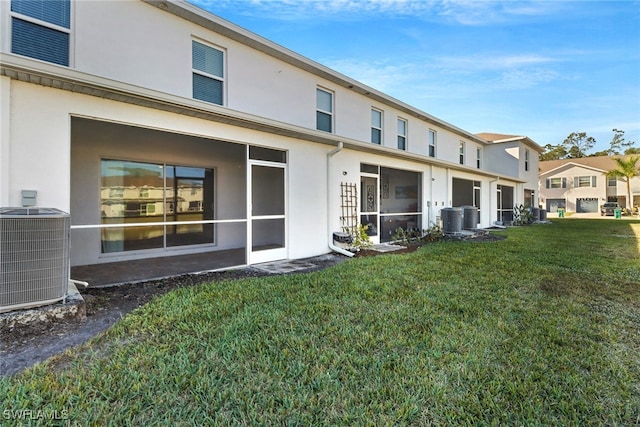 rear view of house with central air condition unit and a lawn