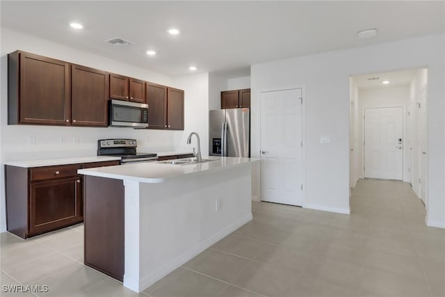 kitchen featuring a center island with sink, stainless steel appliances, dark brown cabinets, and sink