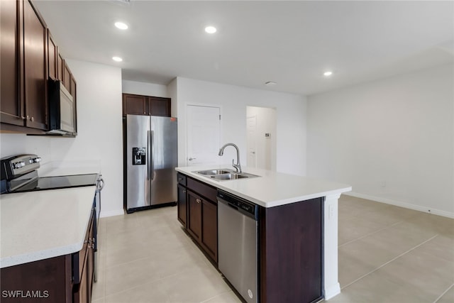 kitchen with appliances with stainless steel finishes, dark brown cabinets, sink, an island with sink, and light tile patterned flooring