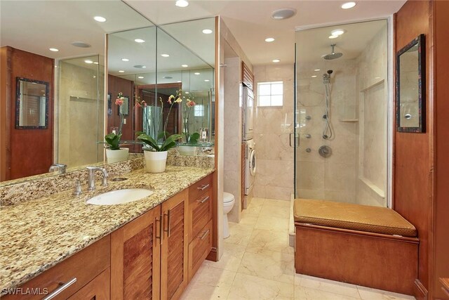 bathroom with toilet, vanity, stacked washer and clothes dryer, and tiled shower