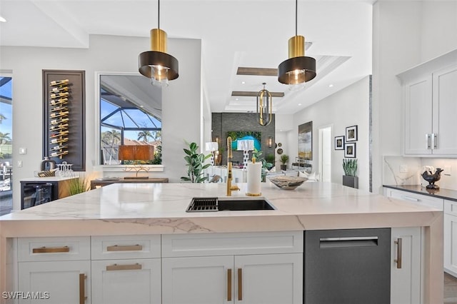 kitchen with white cabinets, decorative light fixtures, and a center island with sink