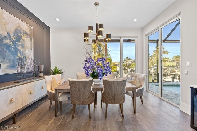 dining area with dark wood-type flooring and an inviting chandelier