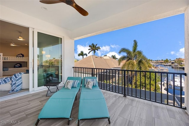 balcony with ceiling fan and a water view