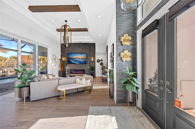 foyer entrance with a fireplace, recessed lighting, a raised ceiling, a towering ceiling, and light wood-type flooring