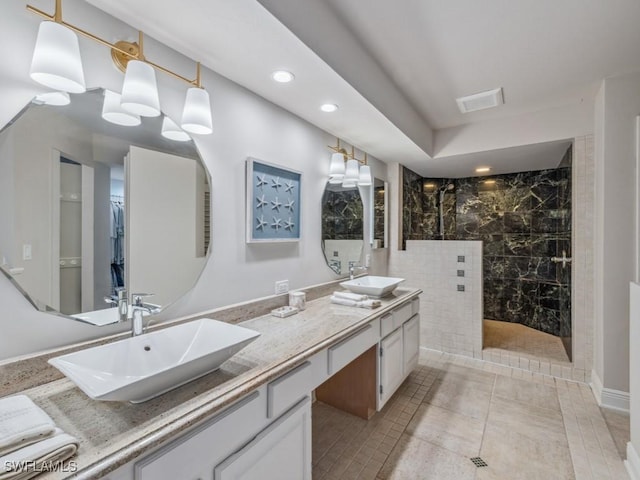 bathroom with a tile shower, vanity, and tile patterned floors