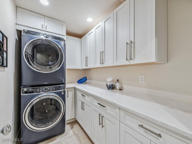 laundry room featuring cabinets and stacked washer / dryer