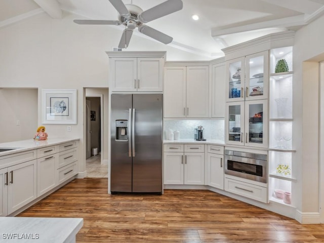 kitchen with lofted ceiling with beams, white cabinets, stainless steel appliances, and wood-type flooring