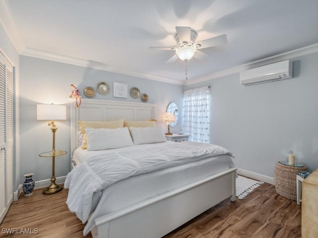 bedroom with a wall mounted AC, crown molding, ceiling fan, hardwood / wood-style flooring, and a closet