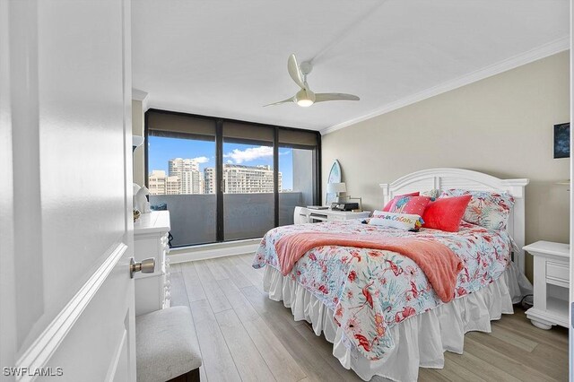 bedroom with ceiling fan, light hardwood / wood-style floors, a wall of windows, and crown molding