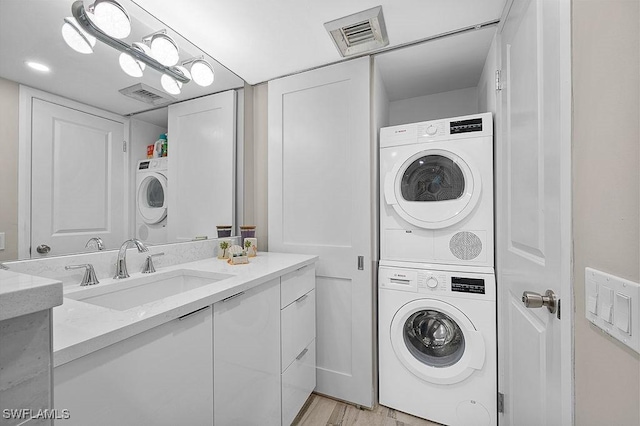 laundry room featuring light hardwood / wood-style floors, sink, and stacked washer and dryer