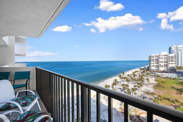 balcony with a water view and a view of the beach