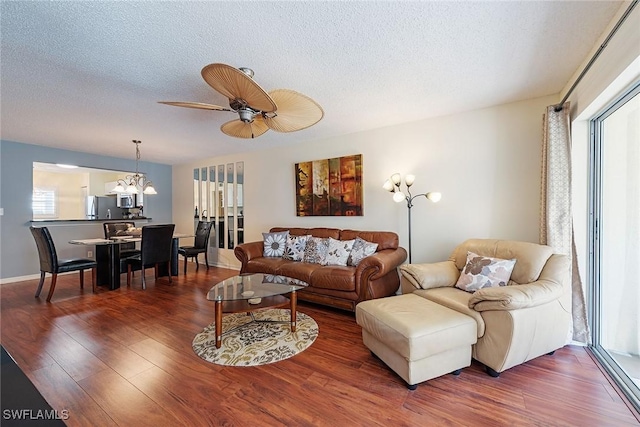 living room with hardwood / wood-style floors, ceiling fan with notable chandelier, and a textured ceiling