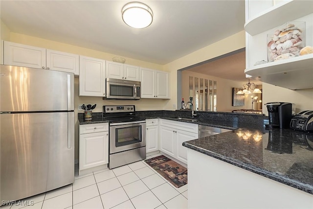 kitchen featuring dark stone counters, stainless steel appliances, sink, light tile patterned floors, and white cabinets