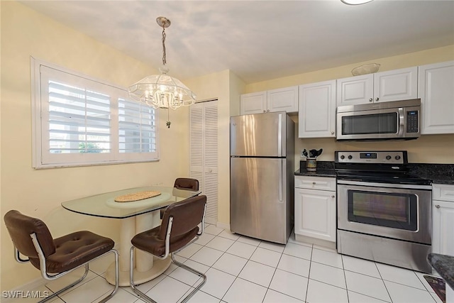 kitchen with hanging light fixtures, light tile patterned floors, white cabinetry, stainless steel appliances, and a chandelier