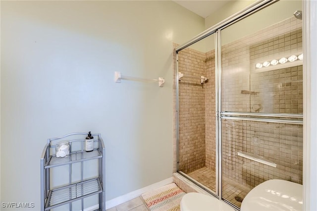 bathroom featuring tile patterned floors, toilet, and a shower with door