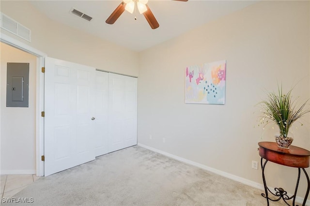 unfurnished bedroom featuring electric panel, light carpet, a closet, and ceiling fan