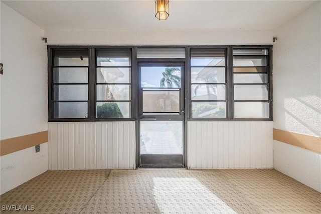 doorway to outside with wood walls