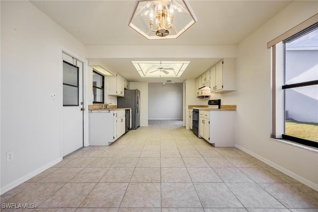 kitchen featuring electric stove, pendant lighting, stainless steel fridge, and white cabinets