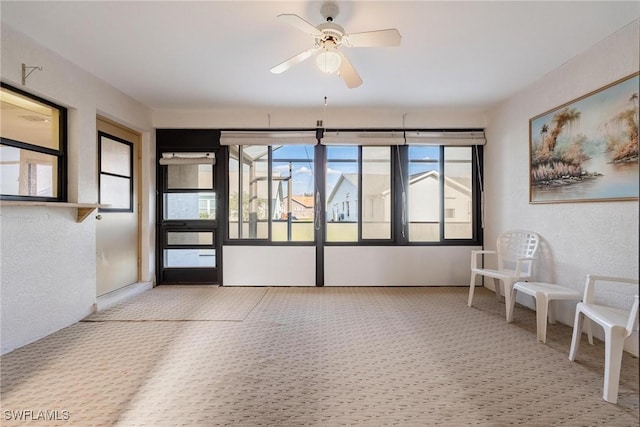 interior space with ceiling fan and light colored carpet