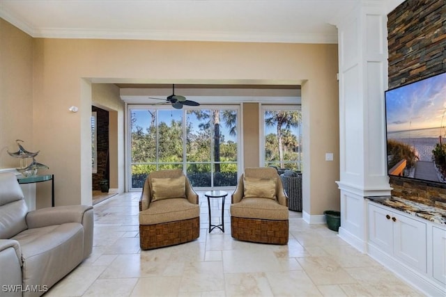 living area featuring decorative columns, ceiling fan, and ornamental molding