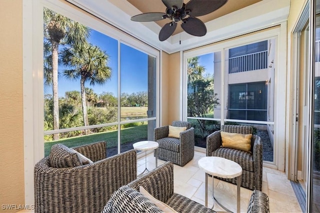 sunroom featuring a raised ceiling and ceiling fan