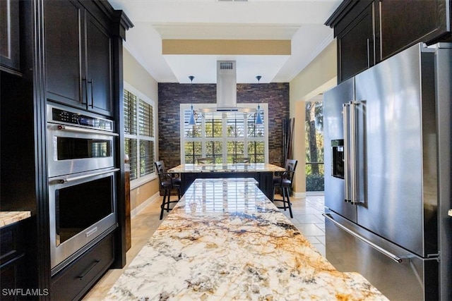 kitchen with light stone counters, brick wall, appliances with stainless steel finishes, light tile patterned floors, and ornamental molding