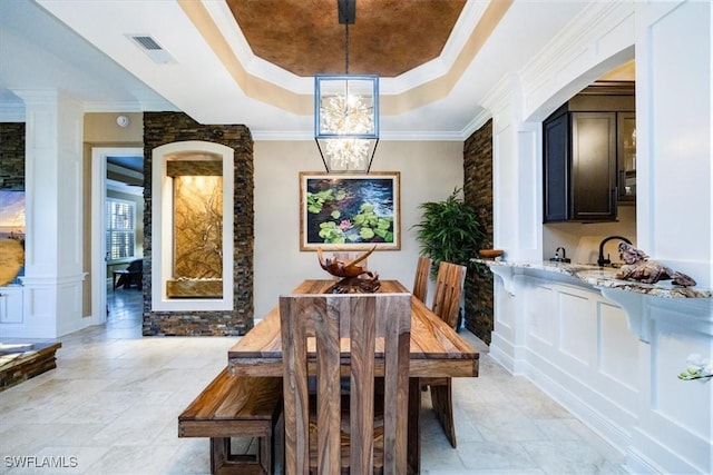 dining space featuring an inviting chandelier, ornamental molding, a raised ceiling, and sink