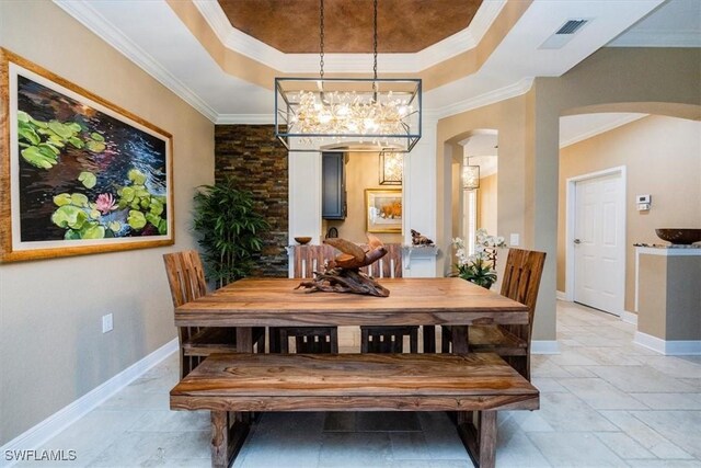 dining area with a raised ceiling, crown molding, and a notable chandelier