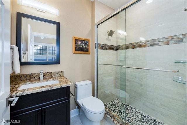 bathroom featuring vanity, toilet, and a shower with shower door