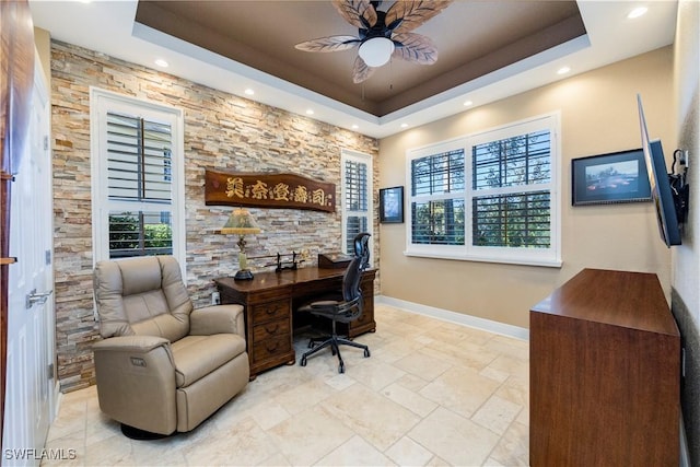 home office with a tray ceiling and ceiling fan