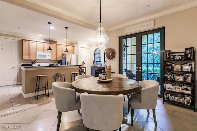 dining area with an inviting chandelier, light tile patterned floors, ornamental molding, and french doors