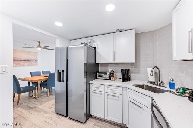 kitchen with sink, white cabinets, light hardwood / wood-style floors, and appliances with stainless steel finishes