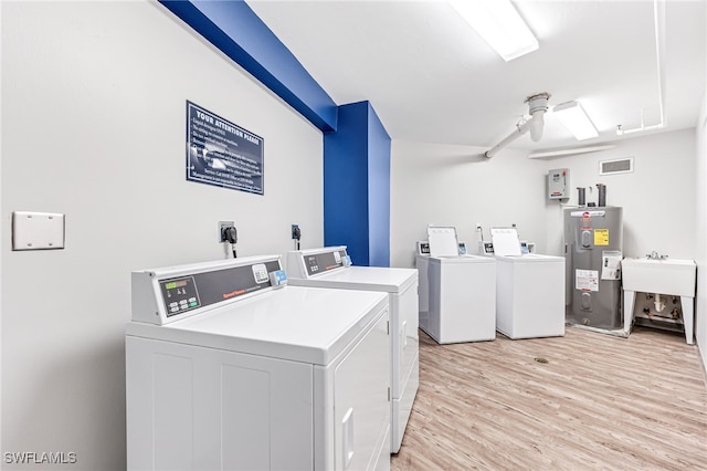 clothes washing area featuring ceiling fan, sink, separate washer and dryer, electric water heater, and light hardwood / wood-style flooring