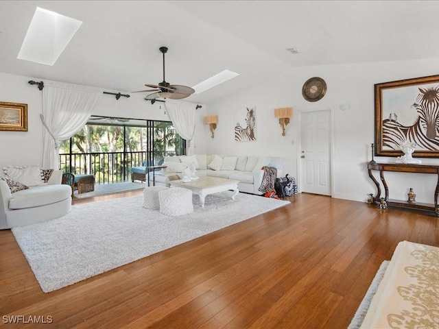 living room featuring hardwood / wood-style flooring, ceiling fan, and vaulted ceiling with skylight