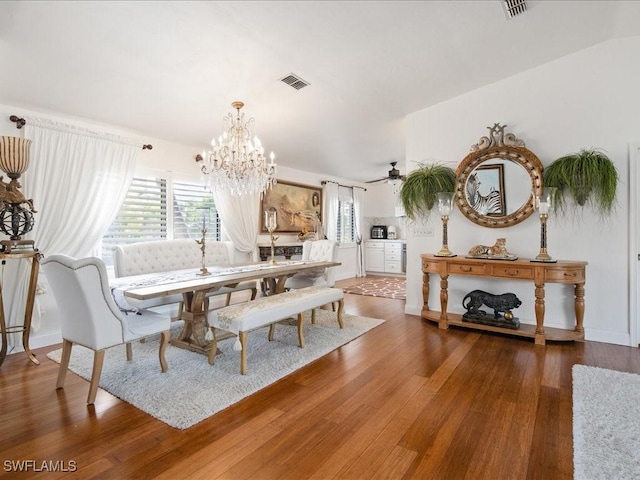 dining space featuring ceiling fan with notable chandelier and dark wood-type flooring