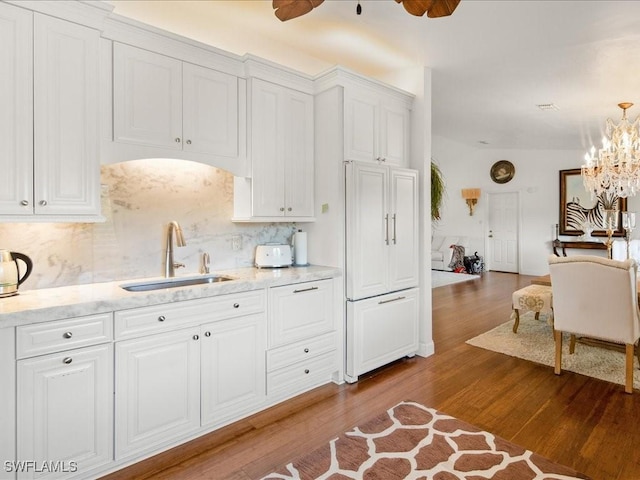 kitchen with white cabinets, light wood-type flooring, tasteful backsplash, and sink