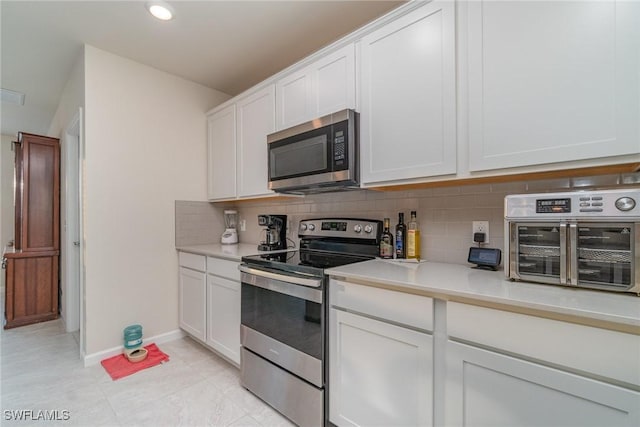 kitchen with white cabinets, decorative backsplash, and appliances with stainless steel finishes