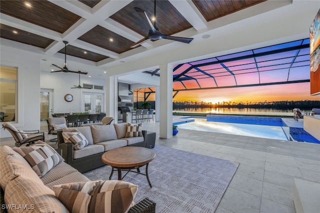 patio terrace at dusk featuring a lanai, an outdoor living space, french doors, and ceiling fan