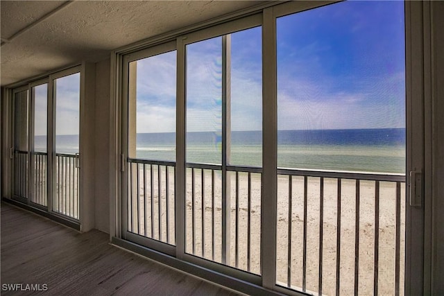 unfurnished sunroom with a water view and a beach view