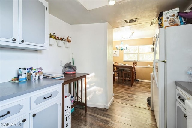 kitchen featuring white cabinets, white refrigerator, dark hardwood / wood-style floors, and a notable chandelier