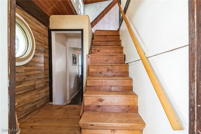 staircase with wood-type flooring and wood walls