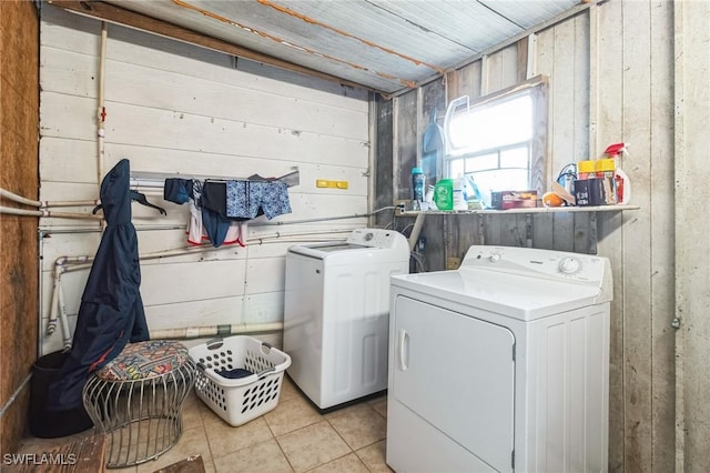 washroom with wood walls, washer and clothes dryer, and light tile patterned floors