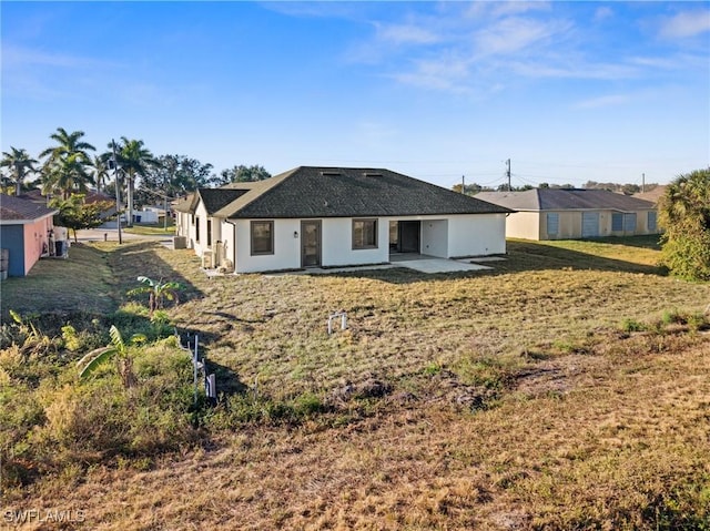 rear view of property featuring a lawn and a patio area