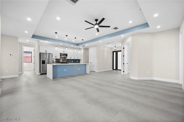 unfurnished living room featuring a tray ceiling, ceiling fan, and sink