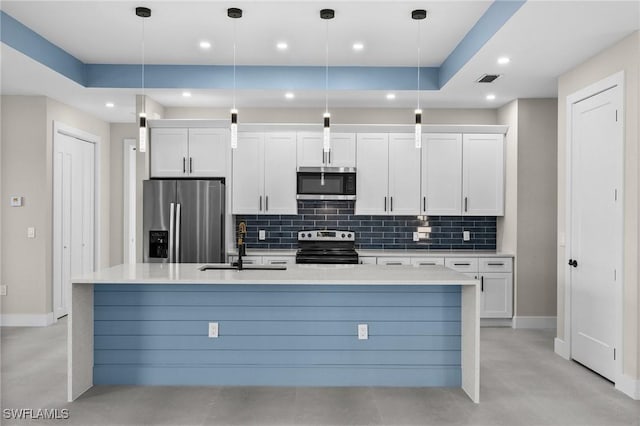 kitchen with white cabinets, appliances with stainless steel finishes, a kitchen island with sink, and pendant lighting