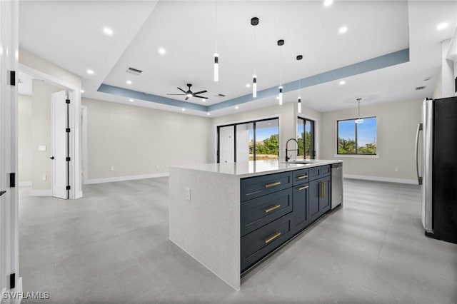 kitchen with stainless steel appliances, a raised ceiling, ceiling fan, a spacious island, and hanging light fixtures