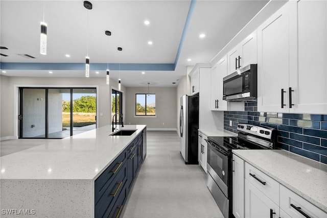 kitchen with white cabinets, appliances with stainless steel finishes, hanging light fixtures, and sink