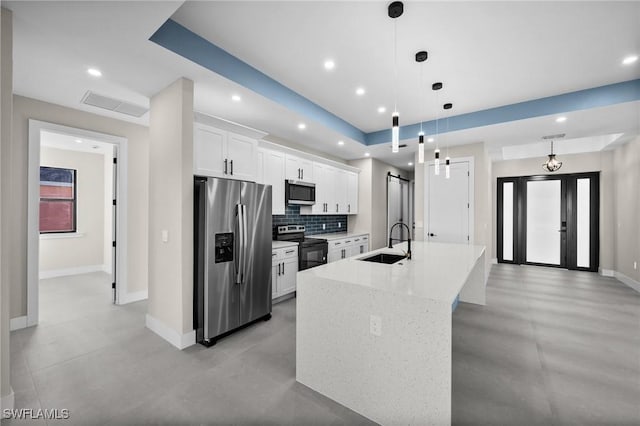 kitchen with white cabinetry, sink, stainless steel appliances, pendant lighting, and a kitchen island with sink