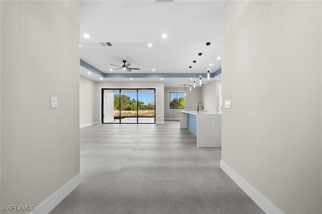 hallway with a tray ceiling and sink